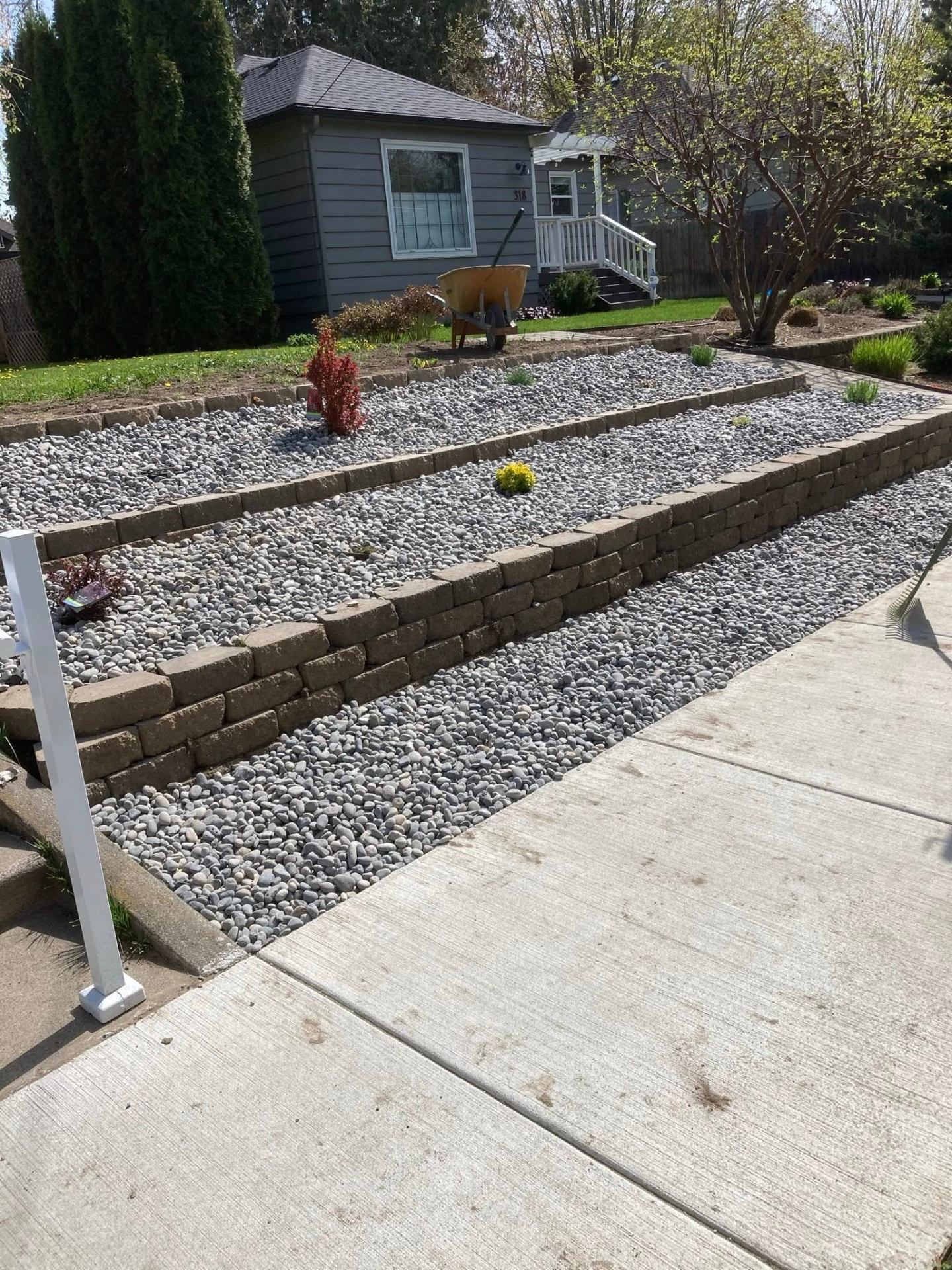 Decorative river-rock landscape bed with tiered low retaining borders